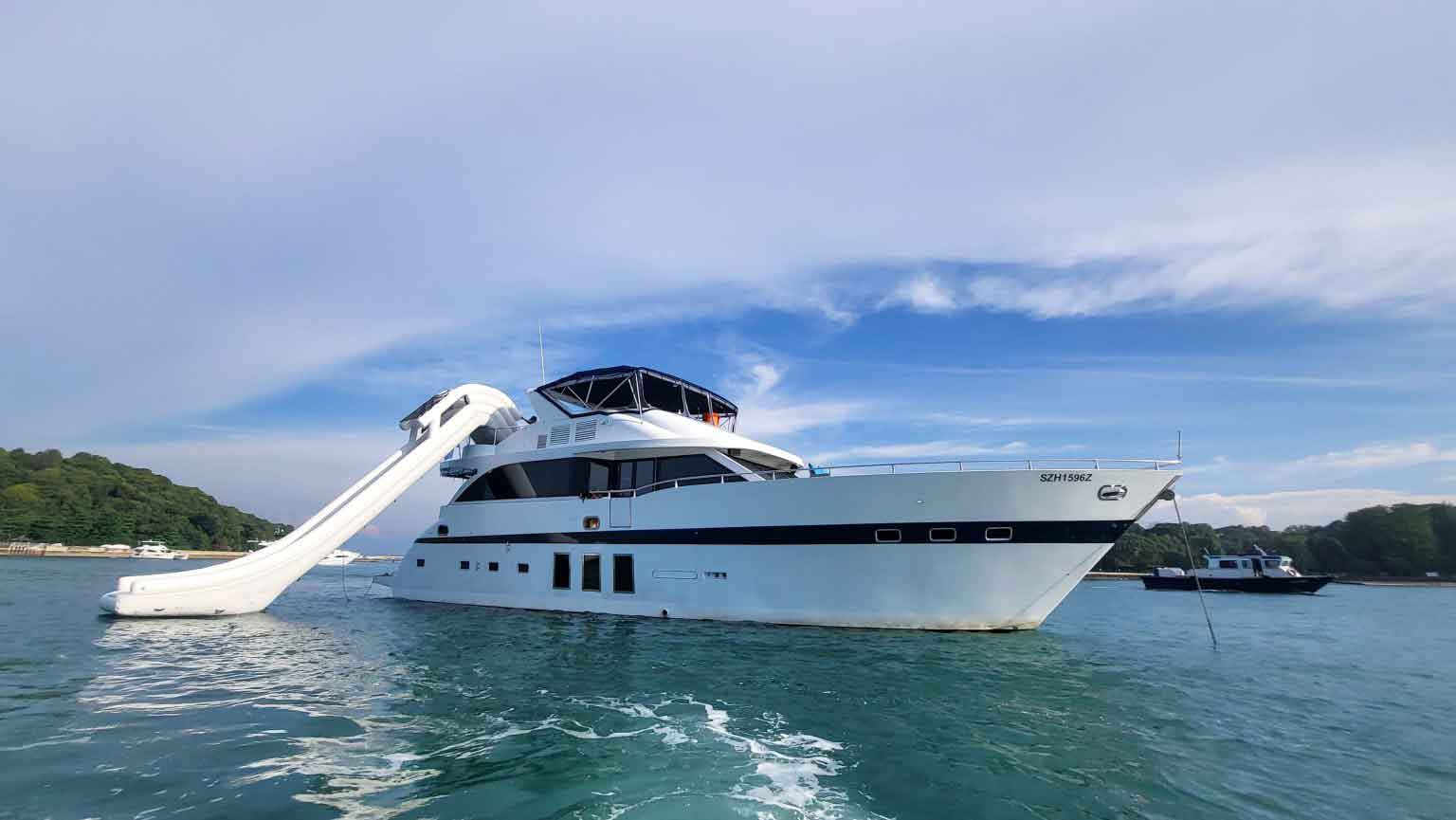 A yacht with a large water slide extending into the sea.