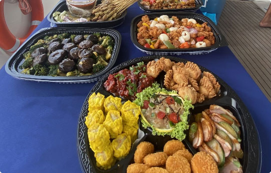 Buffet table with several trays of food.