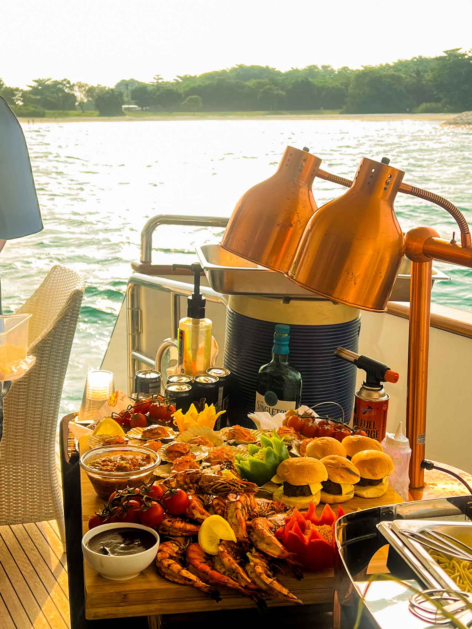 A luxurious buffet on a yacht with grilled prawns, mini burgers, and heat lamps.