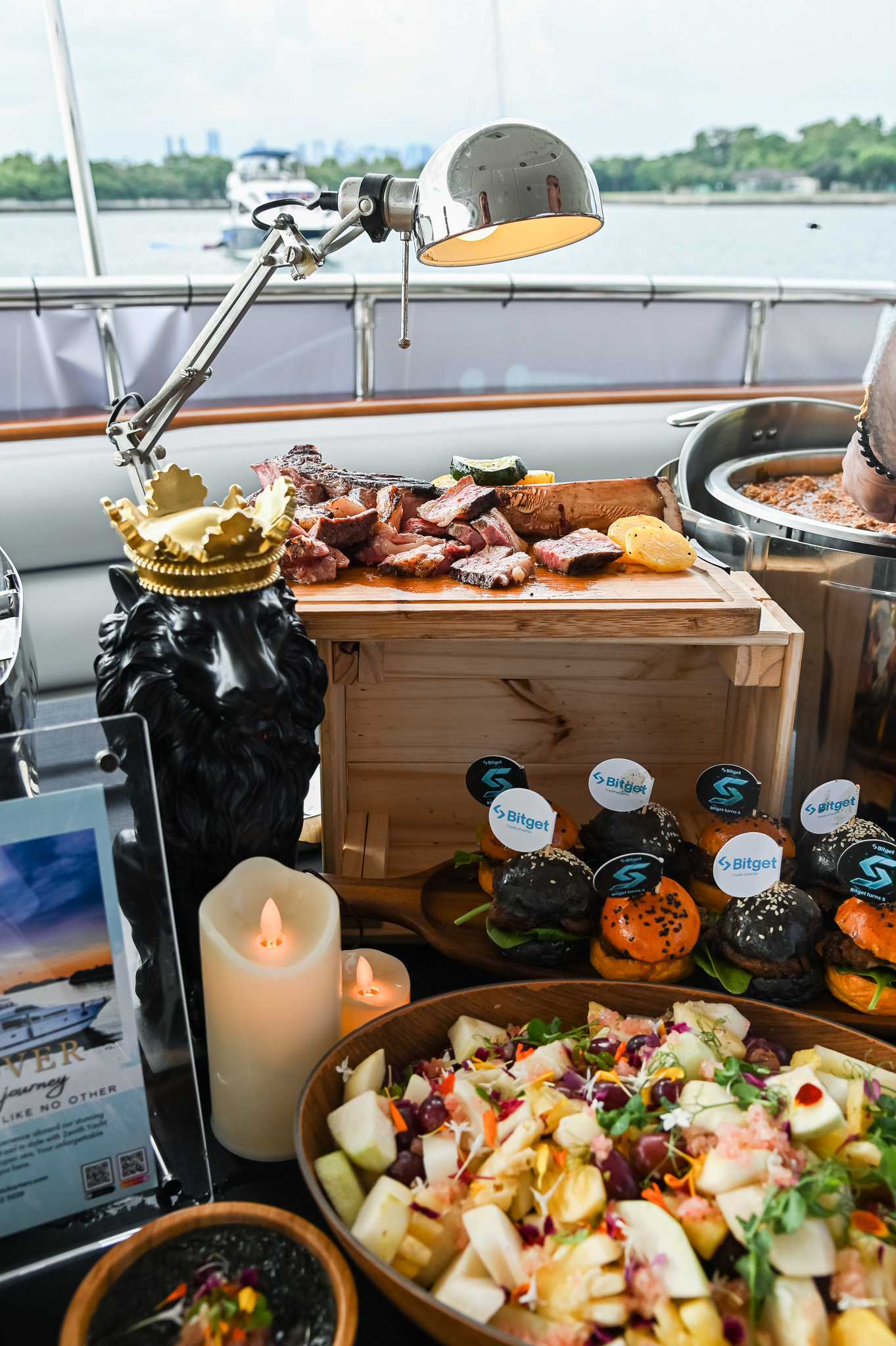 Catered buffet with sliced steak and salads on a yacht deck.