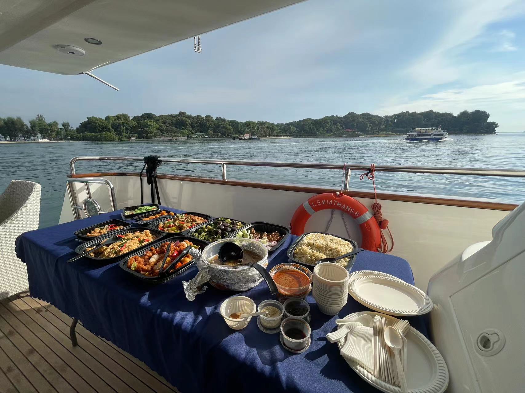 A table filled with a variety of food dishes on the deck of a yacht.