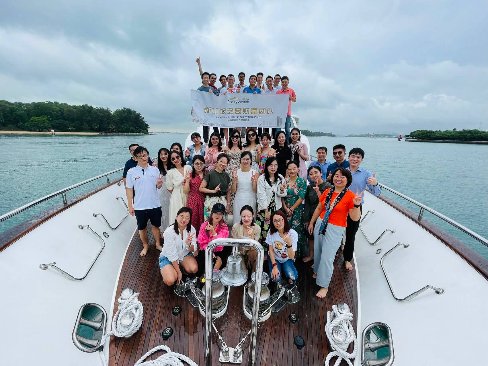 A large group of people posing for a photo on a yacht.