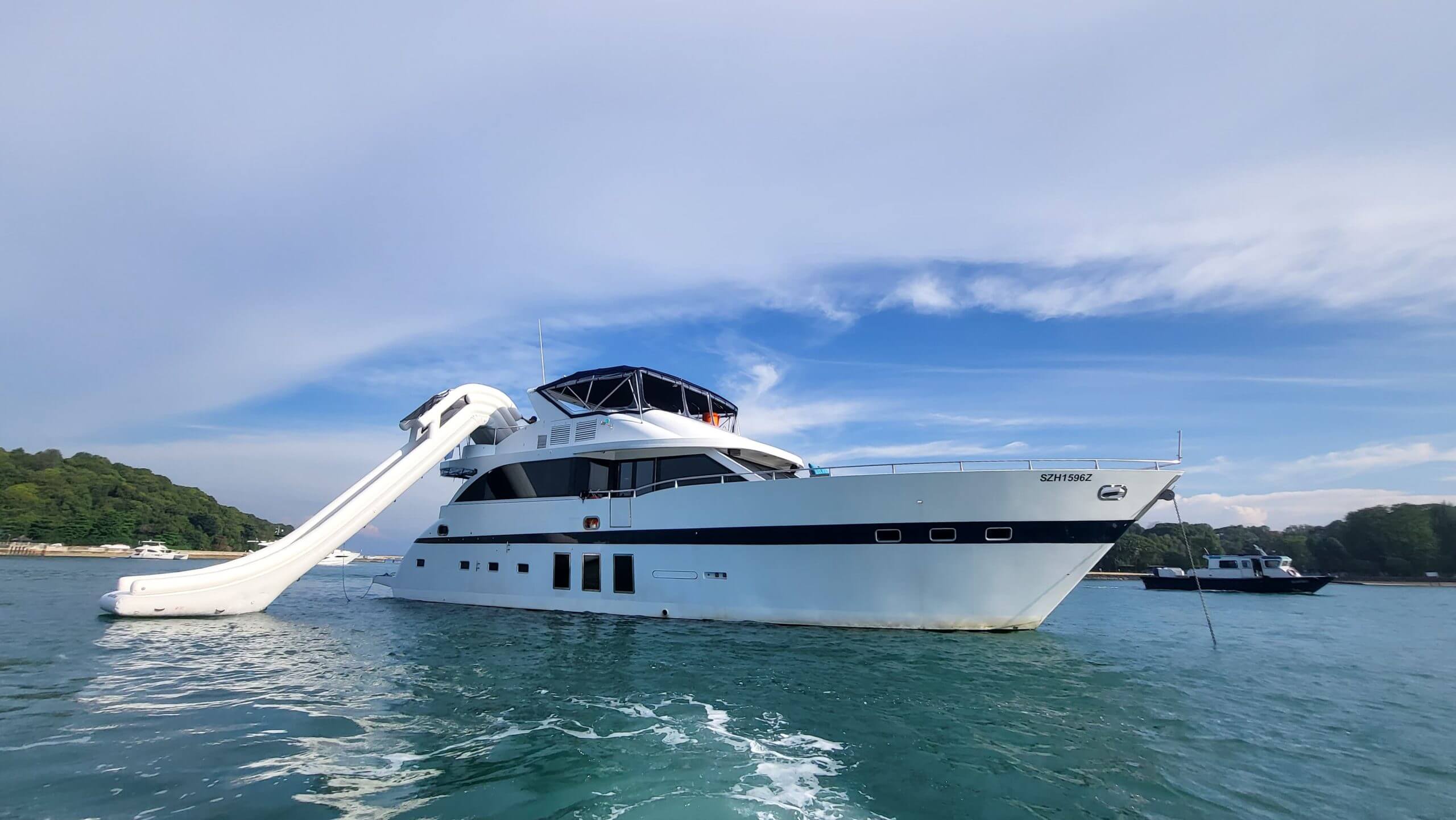 A yacht with a large water slide extending into the sea.