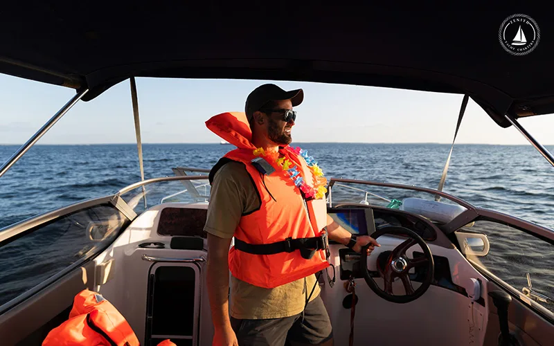 Man-with-a-life-jacket-on-a-yacht-sails-across-serene-waters